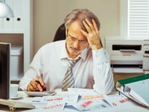 Sad businessman calculating unpaid bills. Bankruptcy concept.